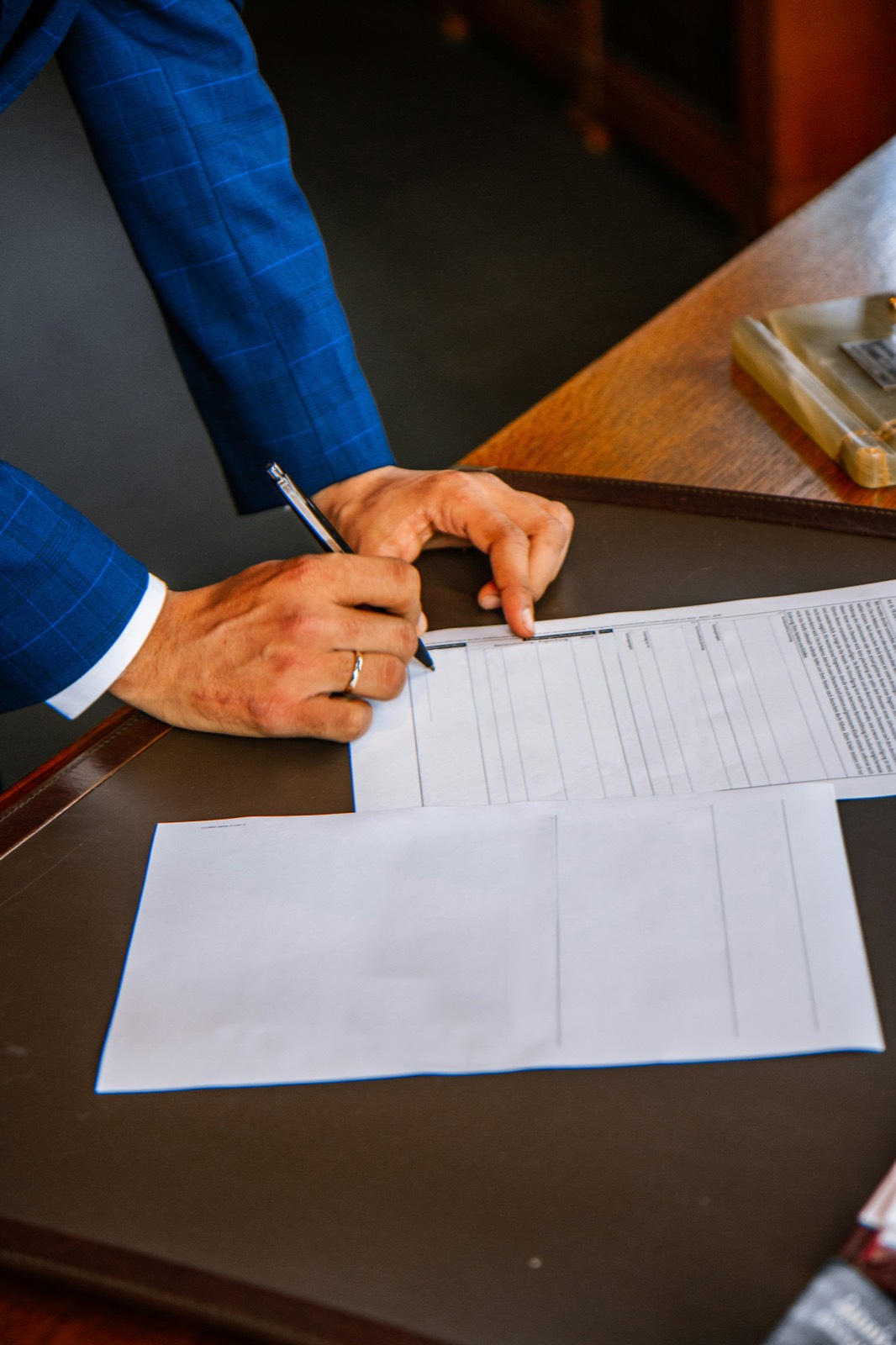 A person in a suit signing documents at a desk